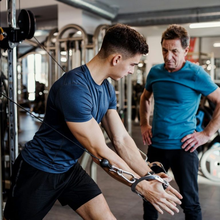 Junger Mann trainiert im Fitnessstudio mit Anleitung eines Trainers. Junger Mann trainiert im Fitnessstudio mit Anleitung eines Trainers.